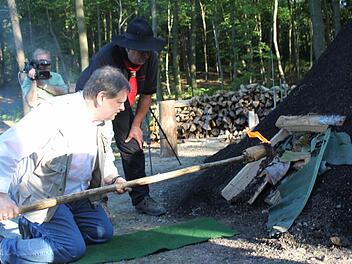 Schirmherr Carl-August Heinz entzündet den Kohlenmeiler. Foto: Veronika Schadeck