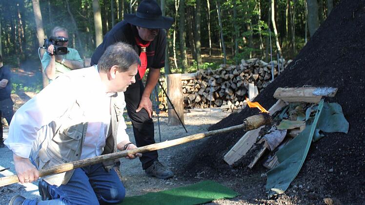 Schirmherr Carl-August Heinz entzündet den Kohlenmeiler. Foto: Veronika Schadeck