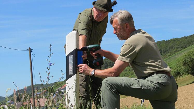 Jagdpächter Oskar Müller und Anton Zisler montieren die Wildwarnreflektoren am Straßenpfosten vor Wirmsthal.  Foto: Doris Bauer