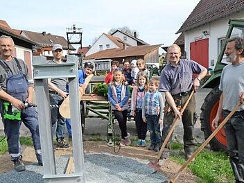 Noch wird Hand angelegt, um ein tragfähiges Fundament mit einem Metallständer für den Maibaum zu errichten (von links) Thomas Welscher (Bulldog-Freunde), Dritter Bürgermeister Markus Wich, Georg Karl (FF), von rechts Helmut Böhnlein (Vorsitzender FF), Ottmar Fugmann (Jagdgenossenschaft) sowie die Landfrauengruppe und einige Kinder, die sich auf den Maibaum freuen.  Foto: Karl-Heinz Hofmann