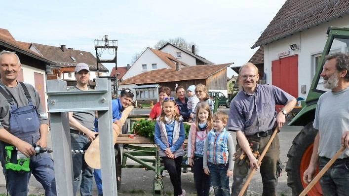 Noch wird Hand angelegt, um ein tragfähiges Fundament mit einem Metallständer für den Maibaum zu errichten (von links) Thomas Welscher (Bulldog-Freunde), Dritter Bürgermeister Markus Wich, Georg Karl (FF), von rechts Helmut Böhnlein (Vorsitzender FF), Ottmar Fugmann (Jagdgenossenschaft) sowie die Landfrauengruppe und einige Kinder, die sich auf den Maibaum freuen.  Foto: Karl-Heinz Hofmann