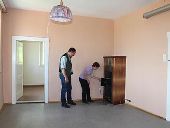 Pfarrer Torsten Bader und Waltraud Gehring vom Kirchenvorstand inspizieren den Ölofen in einem der frisch gestrichenen Räume. Foto: Andreas Dorsch