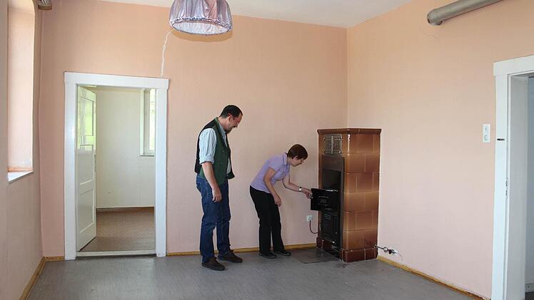 Pfarrer Torsten Bader und Waltraud Gehring vom Kirchenvorstand inspizieren den Ölofen in einem der frisch gestrichenen Räume. Foto: Andreas Dorsch