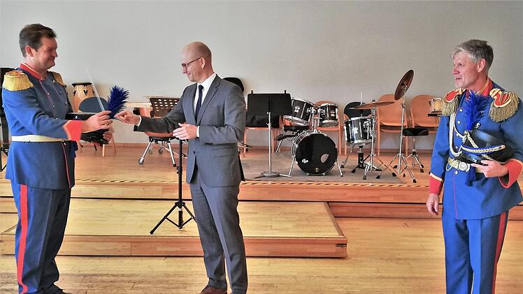 Oberbürgermeister Dirk Vogel (SPD; Mitte) übergibt den Dirigentenstab an den neuen Leiter der Bad Kissinger Musikschule, Matthias Zull; rechts im Bild: der bisherige Stadtmusikdirektor Bernd Hammer.