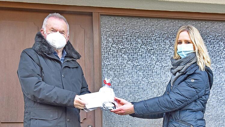 Bürgermeisterin Elisabeth Simmerlein übergibt Geschenke und Masken an den 71-jährigen Erich Langenfelder.  Foto: Karl Heinz Wirth