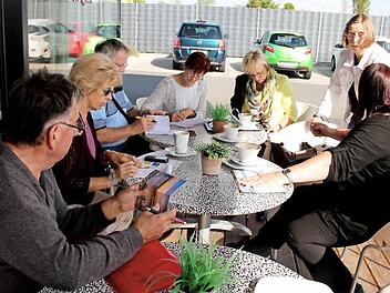 Die Ehrenamtlichen des Helferkreises tragen sich bei ihrem Treffen in die Fahrliste ein. Foto: Johanna Blum