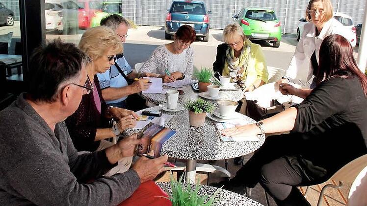 Die Ehrenamtlichen des Helferkreises tragen sich bei ihrem Treffen in die Fahrliste ein. Foto: Johanna Blum