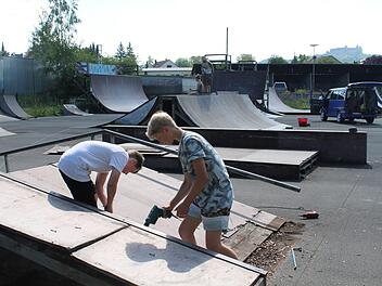 Justin Klaßmann (links) und Nolan Flaßbeck entfernen den Holzbelag der flachen Rampe. Im Hintergrund werkeln Markus Grempel und seine Tochter Mia an der Halfpipe. Foto: Christian Dreßel