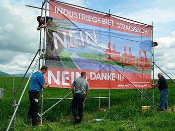 Die Aktivisten der Interessengemeinschaft Stralsbach bringen zwei große Protestbanner an einem Gerüst an. Dieses steht auf einem Feld direkt an der B 286, neben dem das Industriegebiet geplant ist. Foto: Kathrin Kupka-Hahn