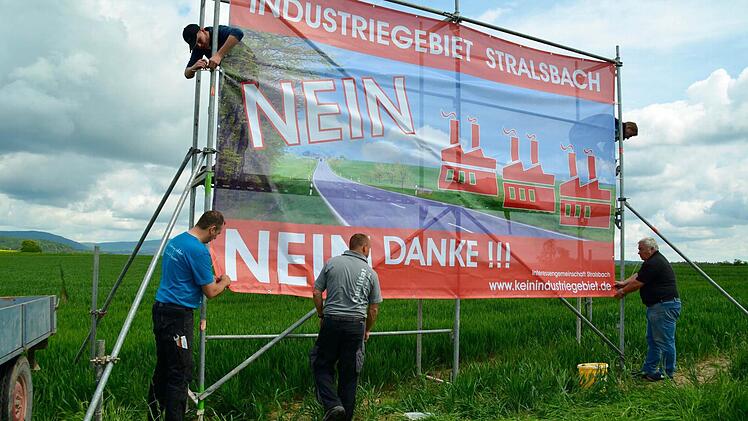 Die Aktivisten der Interessengemeinschaft Stralsbach bringen zwei große Protestbanner an einem Gerüst an. Dieses steht auf einem Feld direkt an der B 286, neben dem das Industriegebiet geplant ist. Foto: Kathrin Kupka-Hahn