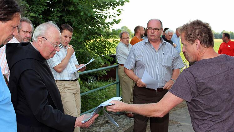 Überflutete Äcker: Interessiert nimmt Pater Franziskus Büll die Lichtbildaufnahmen vom jüngsten Hochwasser von Landwirt Lorenz Bremer entgegen. Foto: Pfannes