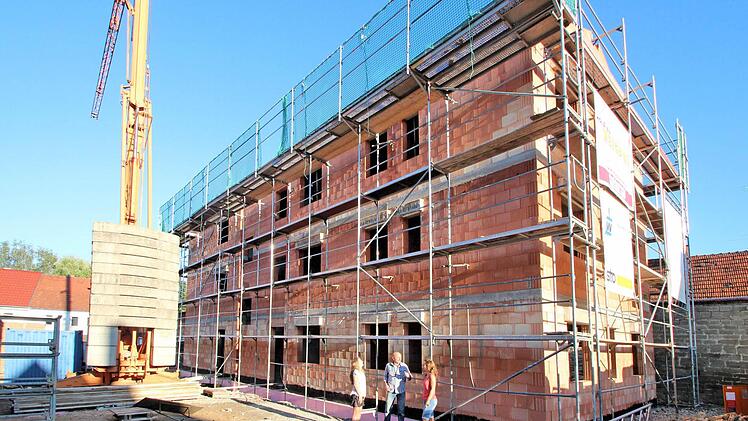 Ein dreistöckiges Haus mit acht Wohnungen entsteht zurzeit in der Hauptstraße 89 in Poppenlauer. Damit wird hier eine wenig schöne Baulücke geschlossen. Unser Bild zeigt im Vordergrund die Bauherren Tanja und Thomas Erdmann mit Tochter Katharina.  Foto: Dieter Britz