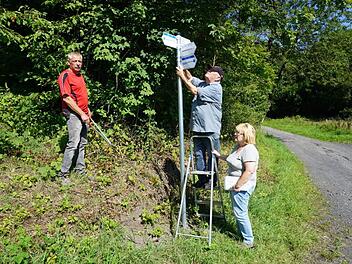 Rigobert Weyer (auf der Leiter) ist seit 45 Jahren für die Wegemarkierung des Rhönklubs Zweigverein Bischofsheim zuständig. Seit zwei Jahren betreut der Bischofsheimer Zweigverein auch die Naturpark-Rundwege. Mit im Bild Frank Gerken (links) und Gabriele Weyer (rechts). Marion Eckert