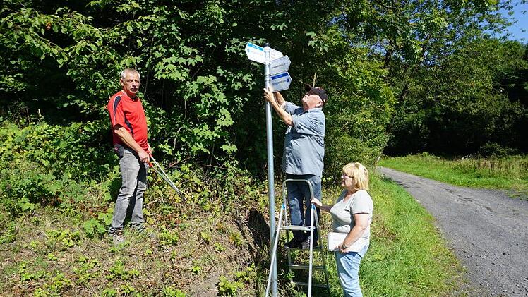 Rigobert Weyer (auf der Leiter) ist seit 45 Jahren für die Wegemarkierung des Rhönklubs Zweigverein Bischofsheim zuständig. Seit zwei Jahren betreut der Bischofsheimer Zweigverein auch die Naturpark-Rundwege. Mit im Bild Frank Gerken (links) und Gabriele Weyer (rechts). Marion Eckert
