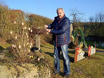 Ortsreferent Egon Kessler hängt Deko-Eier auf. Gemeinsam mit fünf Oehrbergern hat er den Brunnenplatz neugestaltet.  Foto: Kathrin Kupka-Hahn