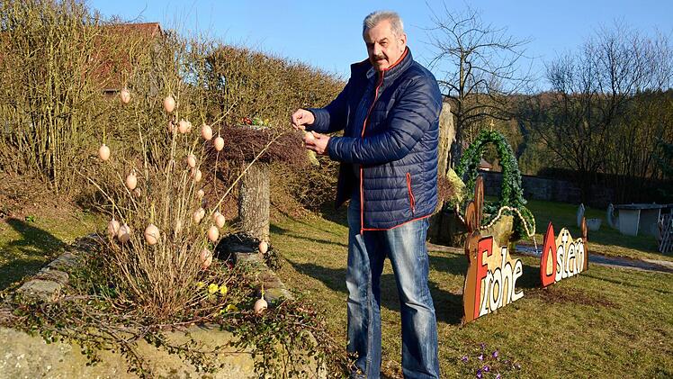 Ortsreferent Egon Kessler hängt Deko-Eier auf. Gemeinsam mit fünf Oehrbergern hat er den Brunnenplatz neugestaltet.  Foto: Kathrin Kupka-Hahn