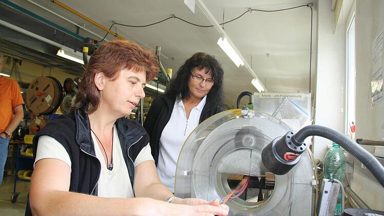 Helga Zeier aus Riedenberg (links) umwickelt einen der letzten Kabelsätze für den Mercedes Vario. Im Hintergrund schaut ihr Elfriede Strigl zu.