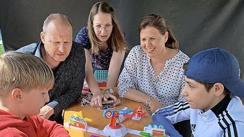 Der Leiter der Hans-Edelmann-Schule, Jochen Kees, und Schulr&auml;tin Kerstin Zapf spielen mit Jason Simon und Mohammad Sabe am Spieletisch.