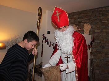 Jannis guckt neugierig in den Sack seines Papas, den Nikolaus.  Foto: Herteux