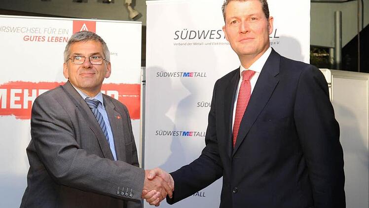 IG Metall Bezirksleiter Jörg Hofmann (li.) und der Vorsitzende der Südwestmetall Rainer Dulger geben sich  nach dem Tarifabschluss für Baden-Württemberg die Hand. Foto: Franziska Kraufmann, dpa