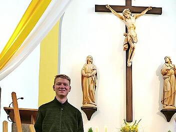 Schützenkönig Julian Pohl steht neben der Schützenscheibe, die das alte Altarbild ziert. Im Hintergrund die Kreuzigungsgruppe.