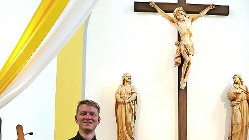 Schützenkönig Julian Pohl steht neben der Schützenscheibe, die das alte Altarbild ziert. Im Hintergrund die Kreuzigungsgruppe.