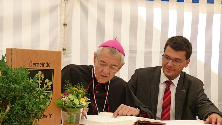 Im Festzelt trug sich Erzbischof Ludwig Schick ins Goldene Buch der Gemeinde Gundelsheim ein, Bürgermeister Jonas Merzbacher schaute zu.