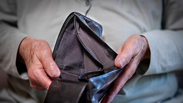 Rentnerin hält leeres Portemonnaie in der Hand
