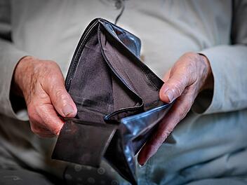 Rentnerin hält leeres Portemonnaie in der Hand