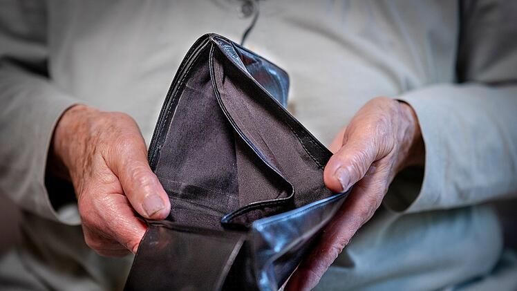 Rentnerin hält leeres Portemonnaie in der Hand