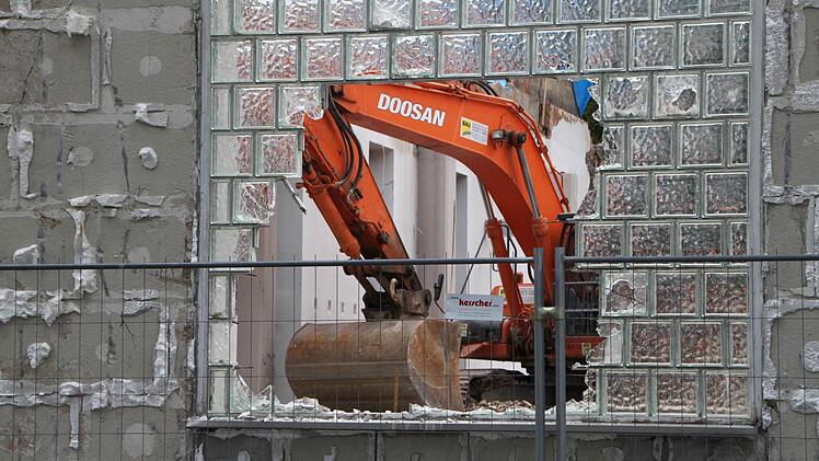 Vor der Glaswand steht ein Bauzaun, dahinter gehen die Arbeiten weiter.