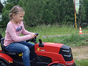 Marie, sechs Jahre alt, probiert zum ersten Mal das Fahren mit dem Traktor. Foto: Daniela Pondelicek