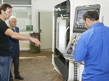 In allen Winkeln fräst und bohrt die hochmoderne Maschine dank 3D-Steuerung und Schwenk-Rundtisch. Die Lehrer Hans-Peter Karl (links) und Helmut Welsch (rechts) erklären dem Landrat Rudolf Handwerker die Funktionsweise des Gerätes, das 150 000 Euro gekostet hat. Foto: sw