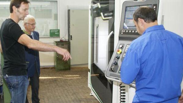 In allen Winkeln fräst und bohrt die hochmoderne Maschine dank 3D-Steuerung und Schwenk-Rundtisch. Die Lehrer Hans-Peter Karl (links) und Helmut Welsch (rechts) erklären dem Landrat Rudolf Handwerker die Funktionsweise des Gerätes, das 150 000 Euro gekostet hat. Foto: sw