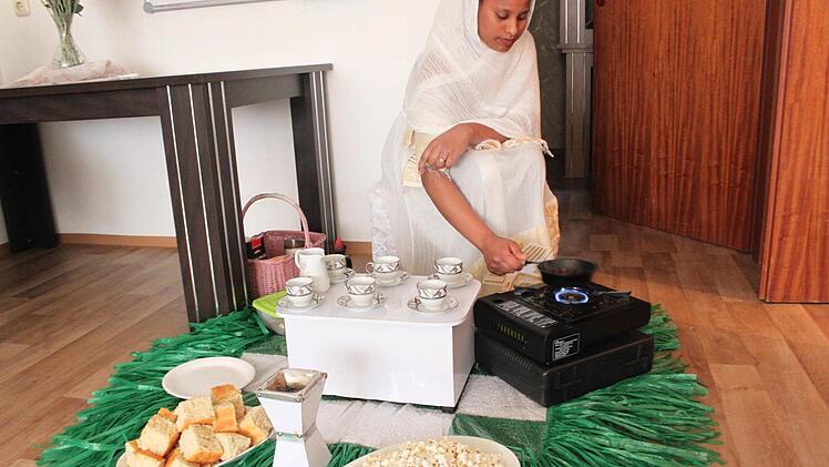 Mabrat Yonas röstet die Kaffeebohnen für die Zeremonie. Auf der Matte aus grünen Plastikgräsern stehen außerdem Tassen, äthiopisches Brot, ein Tongefäß (zum Verbrennen von Kohle und Weihrauch) und Popcorn. Fotos: Ronald Heck