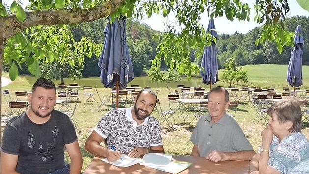 Sami Alijaj unterzeichnet im idyllischen Biergarten den Vertrag. Gemeinsam mit seinem Mitarbeiter Alex Vladulescu (links) hat er das Gasthaus Gumbrecht in Obermembach gepachtet. Hans und Elfriede Gumbrecht freuen sich auf die Nachfolge.  Foto: Bernhard Panzer