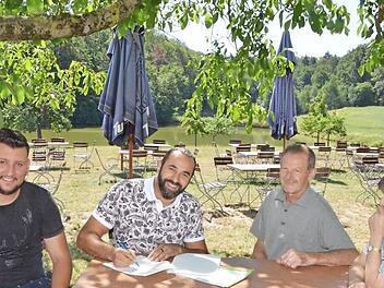 Sami Alijaj unterzeichnet im idyllischen Biergarten den Vertrag. Gemeinsam mit seinem Mitarbeiter Alex Vladulescu (links) hat er das Gasthaus Gumbrecht in Obermembach gepachtet. Hans und Elfriede Gumbrecht freuen sich auf die Nachfolge.  Foto: Bernhard Panzer