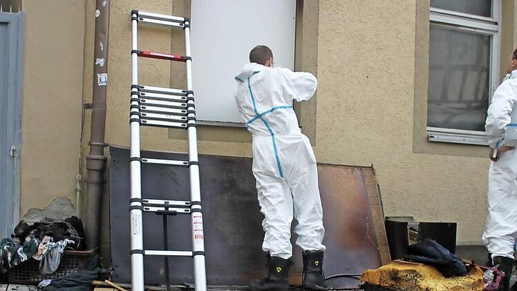 Kriminaltechniker in weißen Anzügen schrauben eine Platte in das Fenster jener Wohnung im Hofmann-Stift in Bad Staffelsteins Bahnhofstraße, in der in der Nacht zum 22. Februar ein 75-jähriger Mann ums Leben gekommen war.  Foto: Lisa Kieslinger