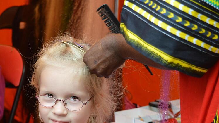 Emilia lässt sich eine lila Stähne ins Haar flechten.