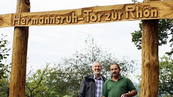 Das   Tor zur  Rhön oberhalb von Stralsbach steht weit auf, geschnitzt hat es mit einer Motorsäge Robert Reuscher  (rechts). Darüber freut sich auch Bürgermeister Waldemar Bug. Foto:  Bartl