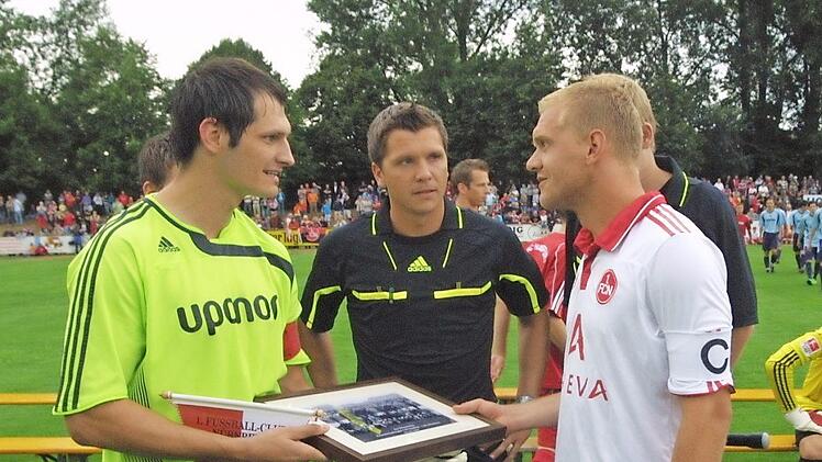 Einer der H&ouml;hepunkte in der j&uuml;ngeren Geschichte des 1. FC Ha&szlig;furt war das Gastspiel des damaligen Fu&szlig;ball-Bundesligisten 1. FC N&uuml;rnberg am 17. Juli 2010 vor 3200 Zuschauern. Die Kapit&auml;ne Thomas Borst (links, FCH) und Andreas Wolf tauschen Erinnerungsgeschenke aus. In der Mitte Schiedsrichter Stein aus Homburg am Rhein.  Foto: G&uuml;nther Geiling
