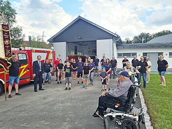 Freudestrahlend und mit Abstand zeigten sich die Wehrleute der Freiwilligen Feuerwehr Burkersdorf mit (von links) Fahnenträger Andreas Gehring und Bürgermeister Bernd Rebhan vor dem neuen Feuerwehrgerätehaus in Burkersdorf. Mit im Bild sind auch Ortssprecher Volker Wündisch (Vierter von links) und einige Zaungäste, die gerne Zeugen des Umzugs ins neue Gerätehaus waren.