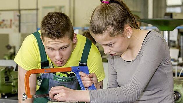 Schaeffler-Azubi Jonas Dressel aus dem ersten Lehrjahr erkl&auml;rt einer Sch&uuml;lerin, worauf man beim S&auml;gen von Metall zu achten hat. Foto: Schaeffler