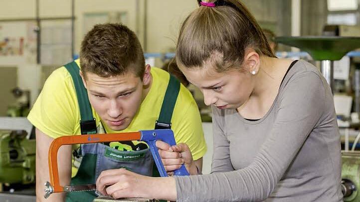 Schaeffler-Azubi Jonas Dressel aus dem ersten Lehrjahr erklärt einer Schülerin, worauf man beim Sägen von Metall zu achten hat. Foto: Schaeffler