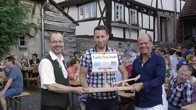 Vorsitzender Paul Schmelz, Saale-Musicum-Organisator Erdinc Yakatul und Bürgermeister Karlheinz Kickuth (von links) bei der Übergabe des Floßes der Veranstaltungsreihe.