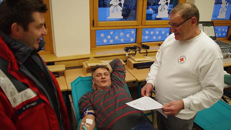 BRK-Ehrenamtsmanager Ralf Schmidt (links) und der Blutspende-Beauftragte vor Ort, Ingbert Weigelt (rechts), freuen sich, dass Konrad Fehn die 16 00 Blutspender-Marke in Windheim geknackt hat.  Fotos: Heike Schülein