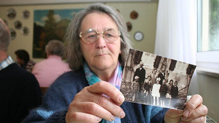 Marga Popp, geborene Martin, mit dem Foto von ihrer Erstkommunion, das sie im Kreise ihrer vielen Geschwistern zusammen mit den Eltern und dem Großvater zeigt.
