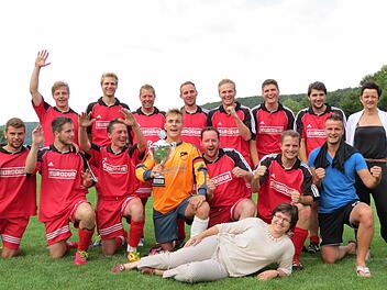 Gruppenbild mit Damen: Die SG Ramsthal/Wirmsthal mit der Verwaltungsgemeinschafts-Vorsitzenden Patricia Schießer (vorne) und der Vorsitzenden des SV Wirmsthal, Andrea Herterich (rechts). Kapitän Fabian Schliebs (Mitte) präsentiert stolz den Pokal. Foto: Doris Bauer