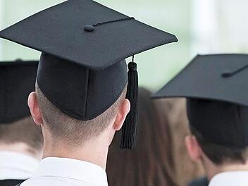 Absolventen sitzen während einer Master-Absolventenfeier in einem Zelt auf dem Gelände der Universität Mannheim. Studenten sehen schlechtere Berufsaussichten wegen Corona. Foto: Silas Stein, dpa
