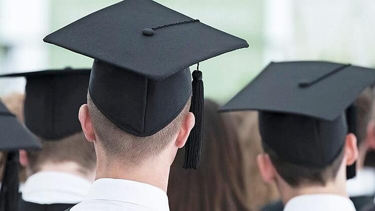Absolventen sitzen während einer Master-Absolventenfeier in einem Zelt auf dem Gelände der Universität Mannheim. Studenten sehen schlechtere Berufsaussichten wegen Corona. Foto: Silas Stein, dpa